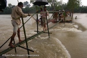 <p>People cross a makeshift bridge made of bamboo. The bridge was built after floods destroyed part of the road.</p>