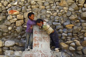 <p>Two boys play at a dried water tap with Maoist graffiti in Yara. (All photos: Gopen Rai)</p>