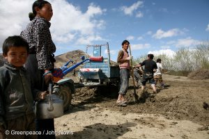 <p>A woman brings tea to local men who shovel mud to make building bricks in Tibet</p>