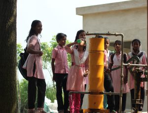 <p>Schoolchildren in West Bengal drink water from an Amrit drinking water purification system connected to a hand pump [image by Indian Institute of Technology Madras]</p>