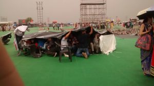 <p>Around 50 media people huddled under a tarp to ward off hail [image by Juhi Chaudhary]</p>