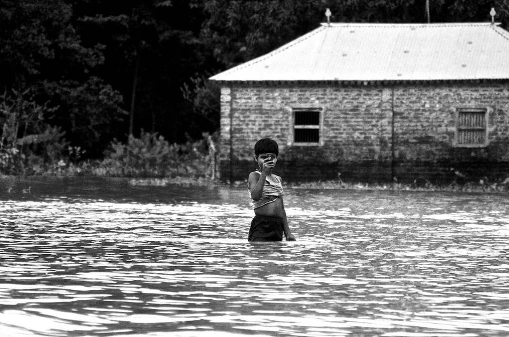 <p>A boy in Chhatapur village in Supaul district of Bihar tries to keep himself and his family entertained by clicking photographs of boats ferrying relief material and people. The inundation was due to a breach in the eastern Kosi embankment in Sunsari district of Nepal. </p>