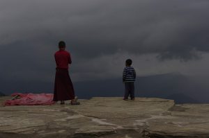 <p>A monk and child stare at an approaching storm at Sanga Choling monastery in Sikkim, India [image by Andrea Kirkby]</p>