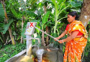 A woman pumps up water from a tubewell in West Bengal despite the red cross that signifies that there is an unacceptable level of arsenic in the water [image by Dilip Banerjee]
