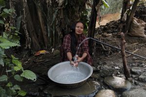 <p>Sharada Bogati of Bidur-9 cleaning dishes beside her home. Unlike many neighbourhoods in Bidur, families in her neighbourhood get enough water for their daily use and also for vegetable farming [image by: Bhrikuti Rai]</p>