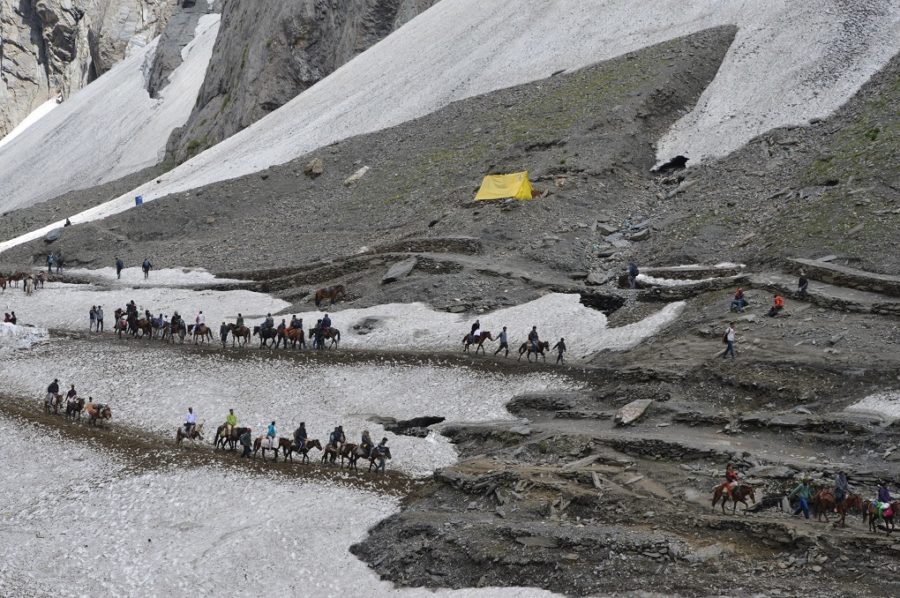 pilgrims on horses trekking across snow towards the Amarnath Cave
