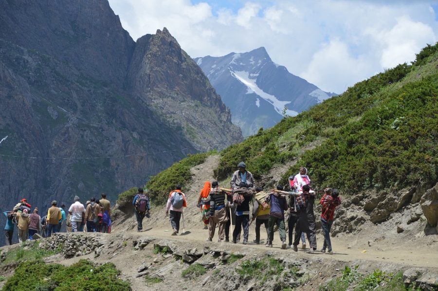 Two pilgrims being carried by local labourers on their shoulders after they performed pilgrimage to Amarnath Cave