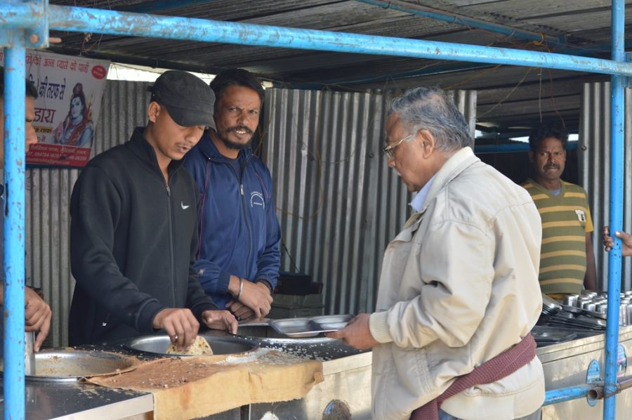 two men serving a pilgrim food at Brari Marg hangar 
