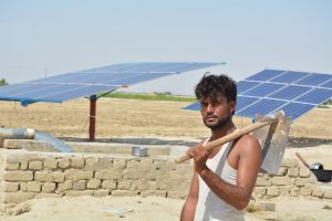 man stands in front of solar powered tube wells, Kachho