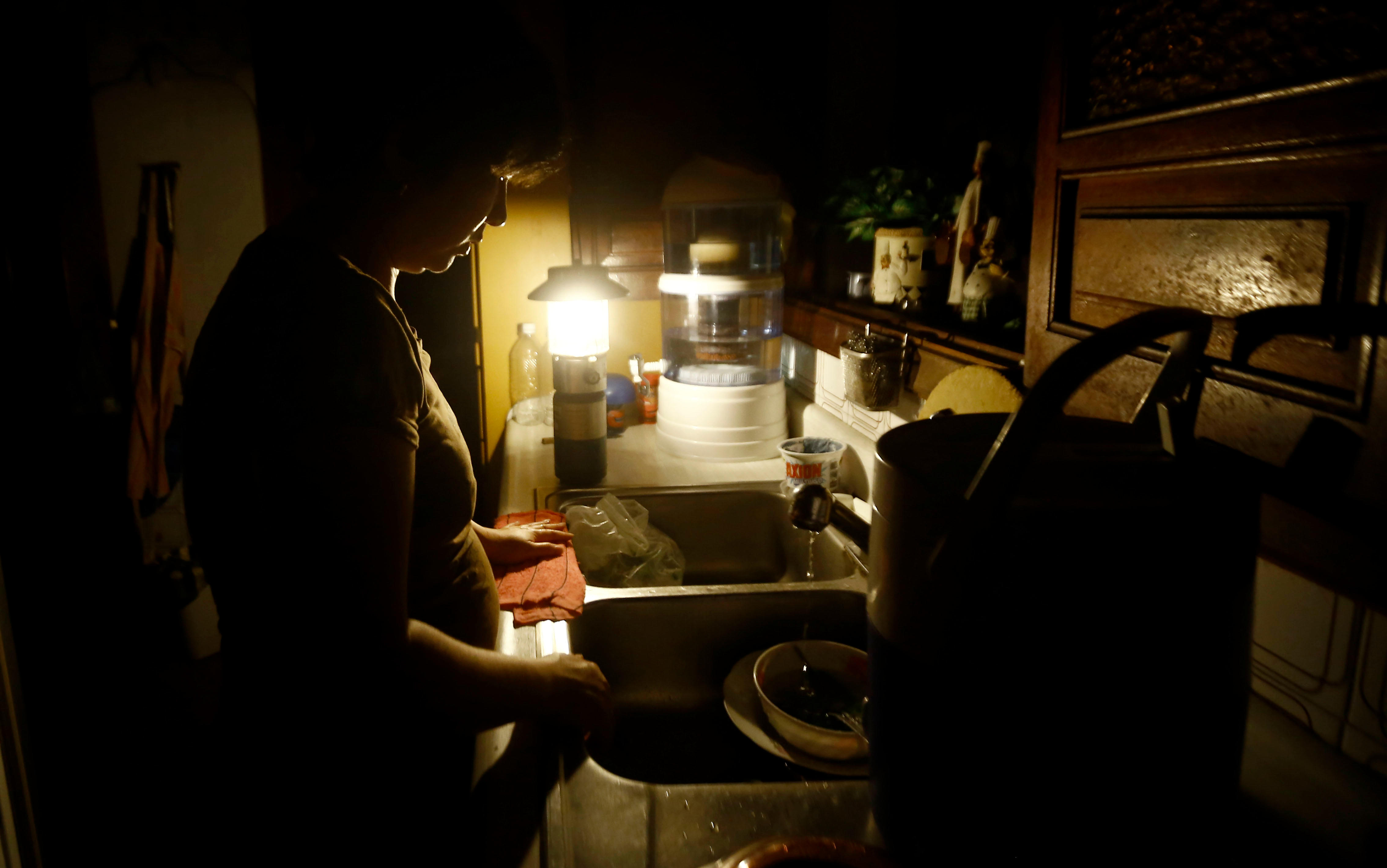 Una mujer lava los platos en medio de un apagón en Venezuela