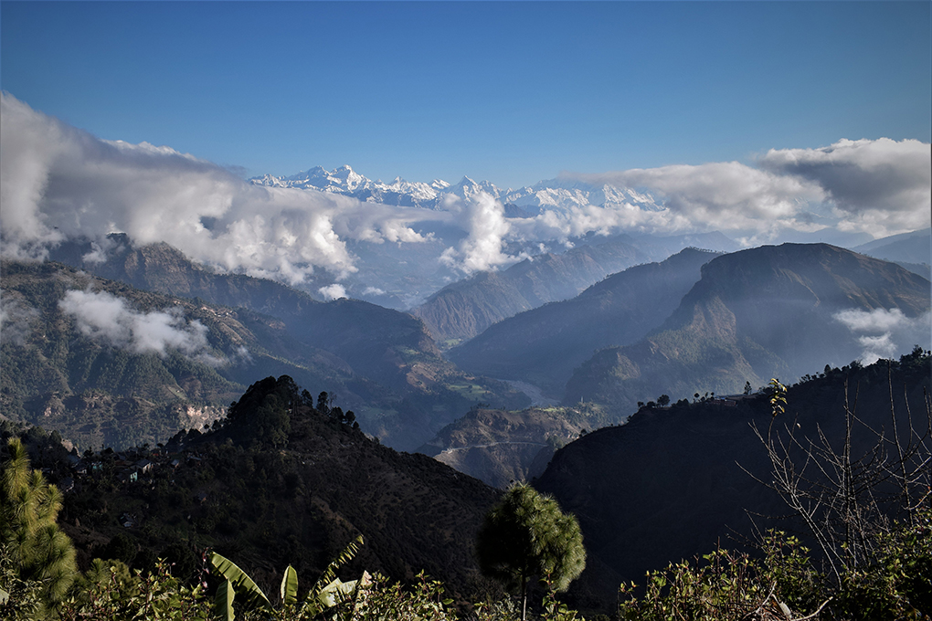 The snowclad Api Himal range of the High Himalayas in the background, with the Mahakali River flowing through richly forested mountains - as seen from the mountains of Dadeldhura, Nepal