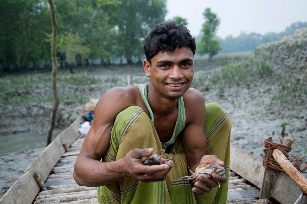 A young fisherman, poses for photographs. He sells crab that he catches from the river in the Sundarbans, in Khulna [image: Alamy]