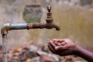 hands cupped to collect water from a tap in India's water crisis