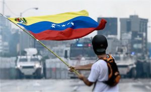 <p>2017年5月，一名抗议者在委内瑞拉国民警卫队前挥舞国旗。图片来源：<a href="https://commons.wikimedia.org/wiki/File:2017_Venezuelan_protests_flag.jpg">Efecto Eco</a></p>