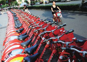 Red hire scheme bikes racked up outside a Hangzhou metro station