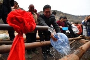 <p>Villagers fill water bottles from a 400-metre-deep well in northern China (Image: Alamy)</p>