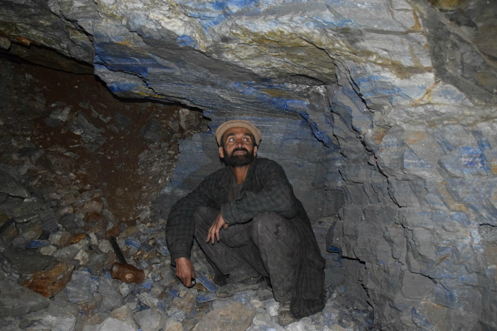 <p>A miner looking at lapis lazuli veins inside a mine.</p>