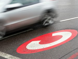 car zooms past road markings for London's congestion charge, a policy that has had mixed environmental results