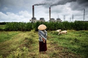 woman stands in front of coal power plant