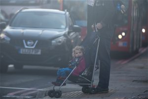 <p>A young child is pushed in a pram across a busy road in London (Image: Elizabeth Dalziel/Greenpeace)</p>