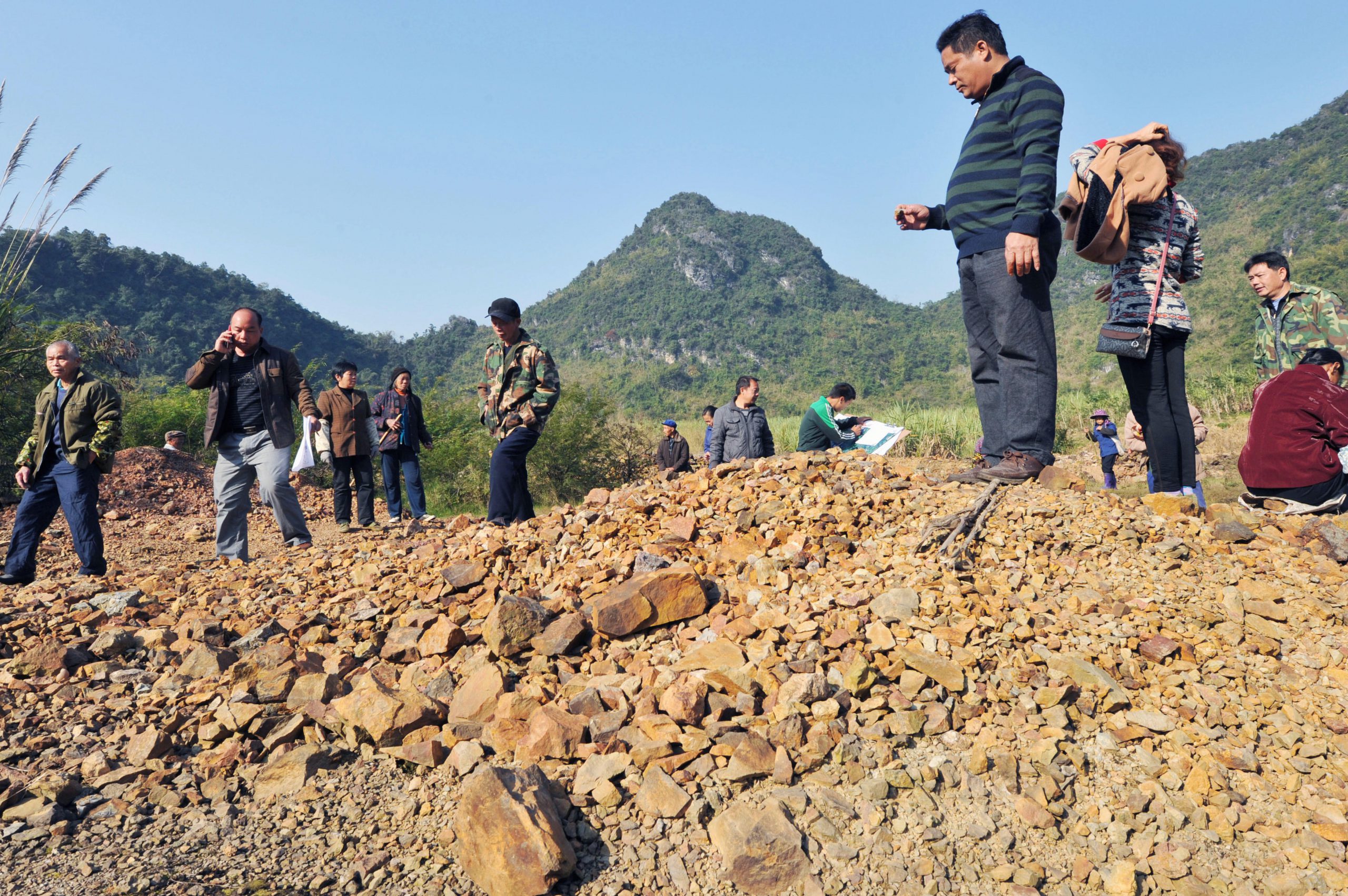 <p>广西省三合镇的村民在疑似污染的农田上。图片来源：Newscom / Alamy</p>