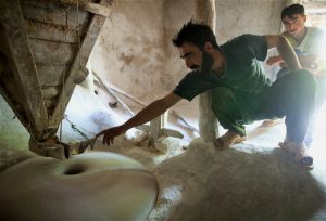 <p>阿富汗帕米尔高原的人们在研磨小麦。图片来源：《亲手撷香》</p>
