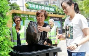 <p>Volunteers help Shanghai residents navigate new waste separation rules. A sign in the background reads: &#8216;Waste sorting is the new fashion&#8217; (Image: Xinhua / Alamy)</p>