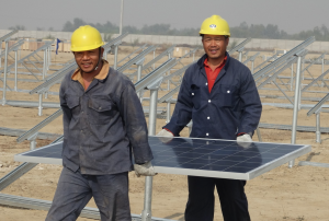 <p>Chinese workers carry one of the 400,000 solar panels installed at the 100MW plant in Pakistan that could eventually be scaled up to 1,000MW, which would make it one of the world&#8217;s largest (Image by Quaid-e-Azam Solar Power (Pvt.) Limited)</p>