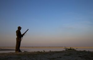 An armed forest guard looking out over the Brahmaputra River. India, Pakistan and Nepal
