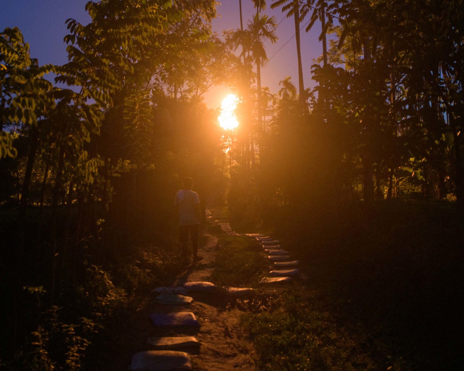 Dilip Mallah walks through the village towards Oitendra Das’s home less than 300 metres away from the burning gas well [Image by: Prakash Bhuyan]