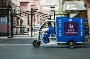 An electric tuktuk transporting household food waste zips past houses on Shanghai