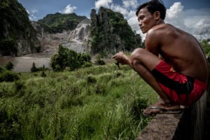 <p>Villager Nuon Oun watches as limestone rock is quarried from the side of Phnom La&#8217;ang, a karst mountain in southern Cambodia (Image: <a href="https://www.rounryphotography.com/" target="_blank" rel="noreferrer noopener">Roun Ry</a> / China Dialogue)</p>