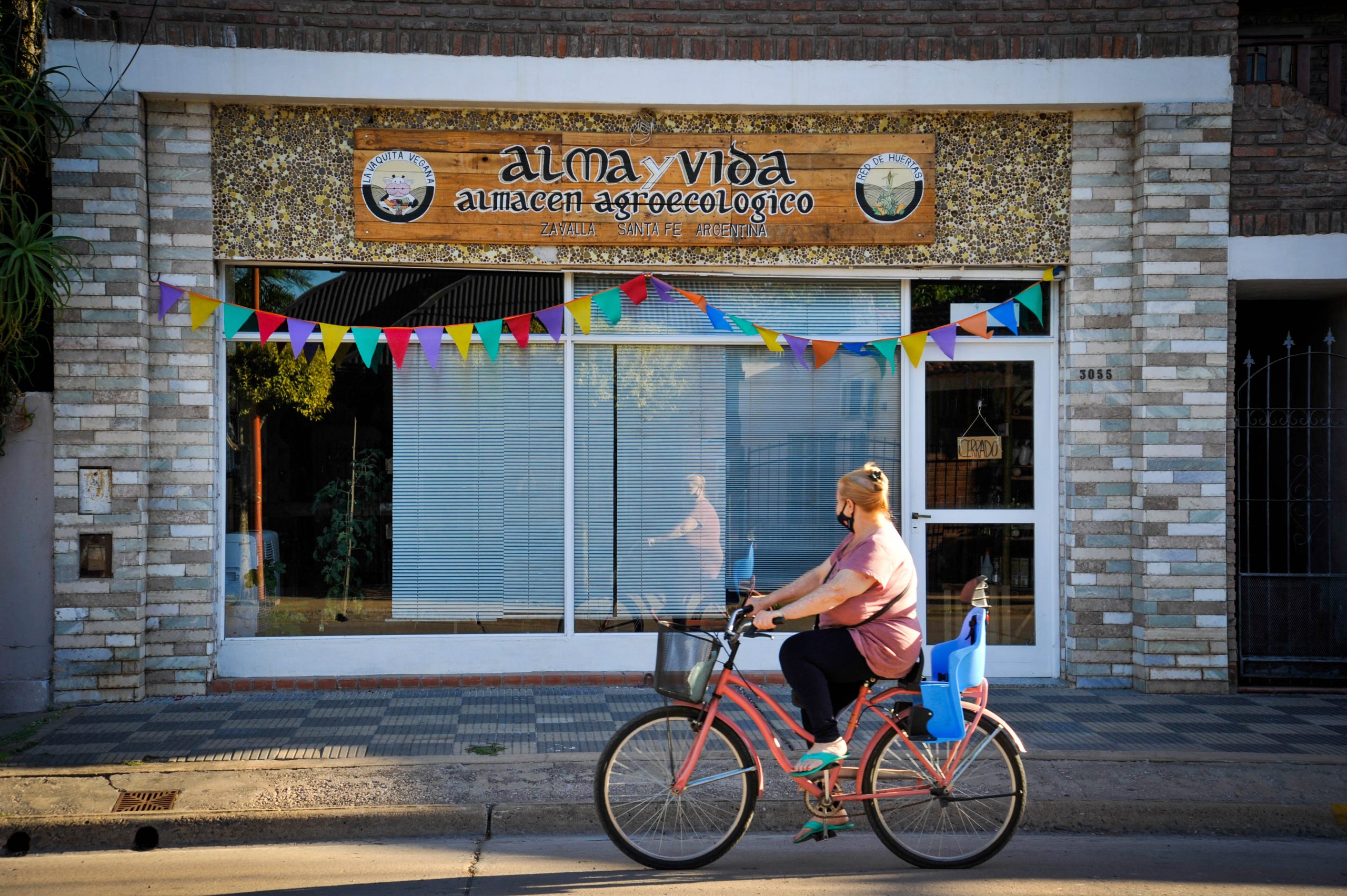 person on a bicycle in front of an agroecological store