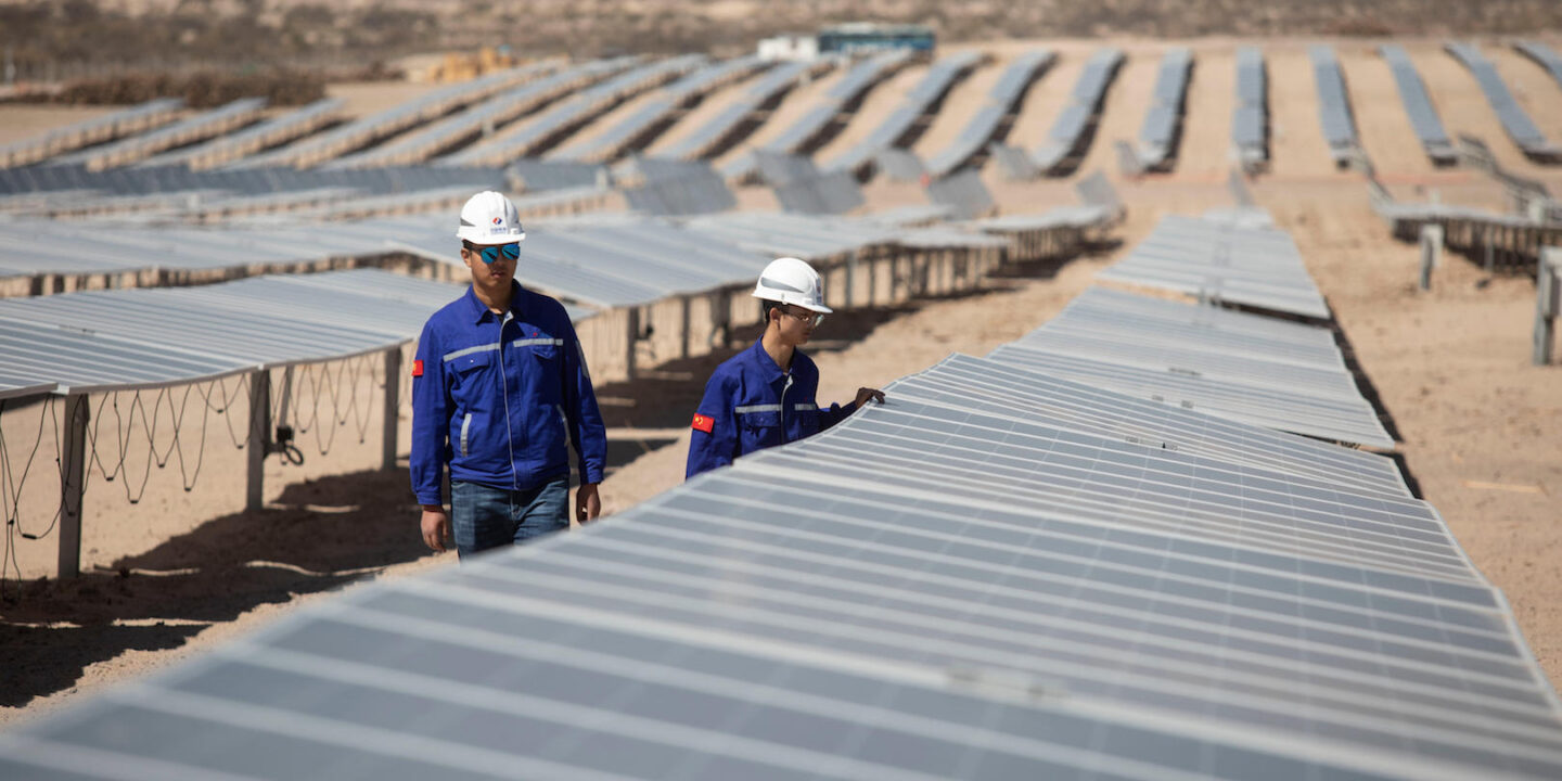 dos personas inspeccionan paneles solares en una planta fotovoltaica