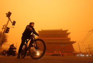 Chinese cycle past a temple shrouded under a thick sandstorm in Beijing on Monday, March 15, 2021