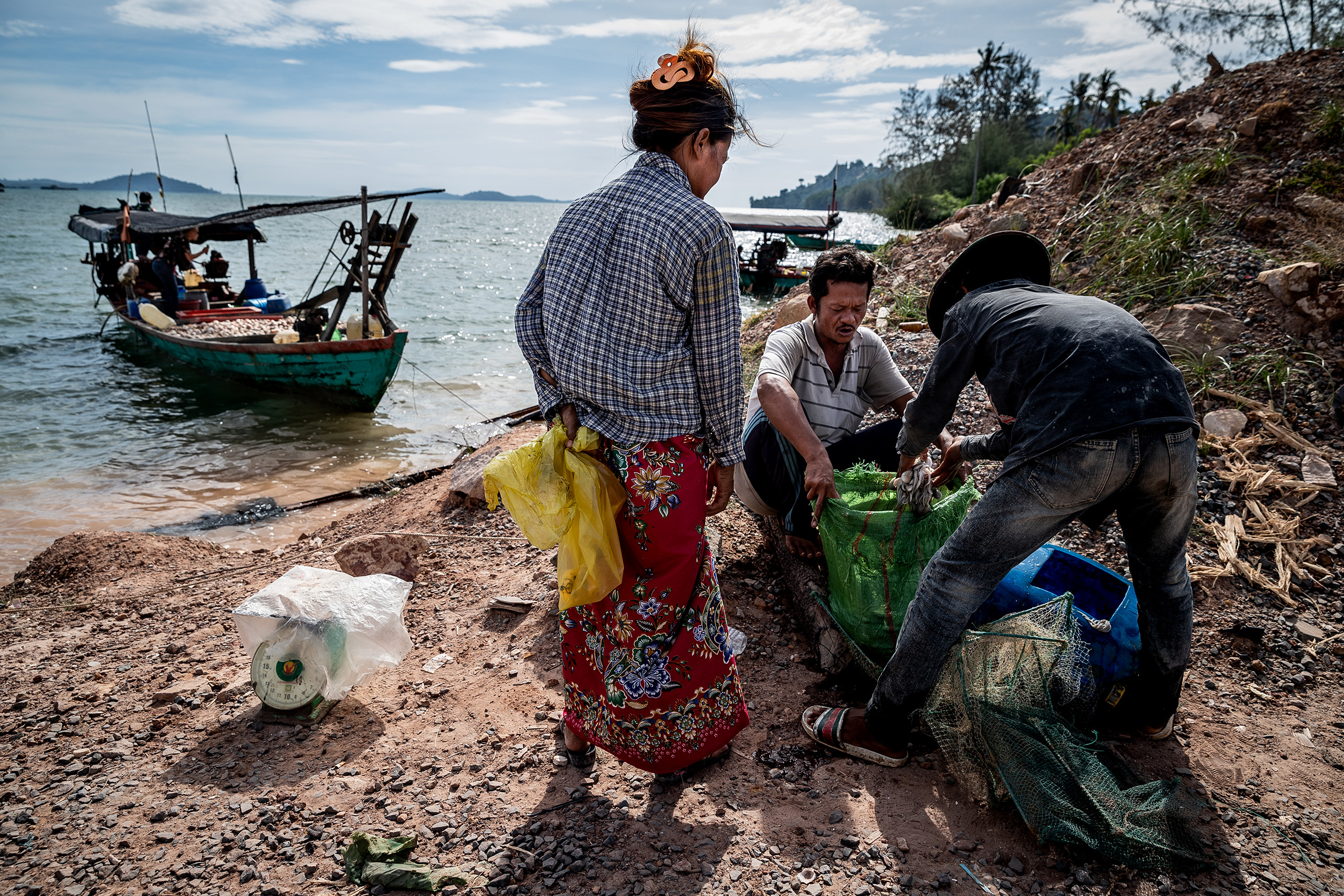 A small-scale fisher sells squid to a local woman near the Canopy Sands development