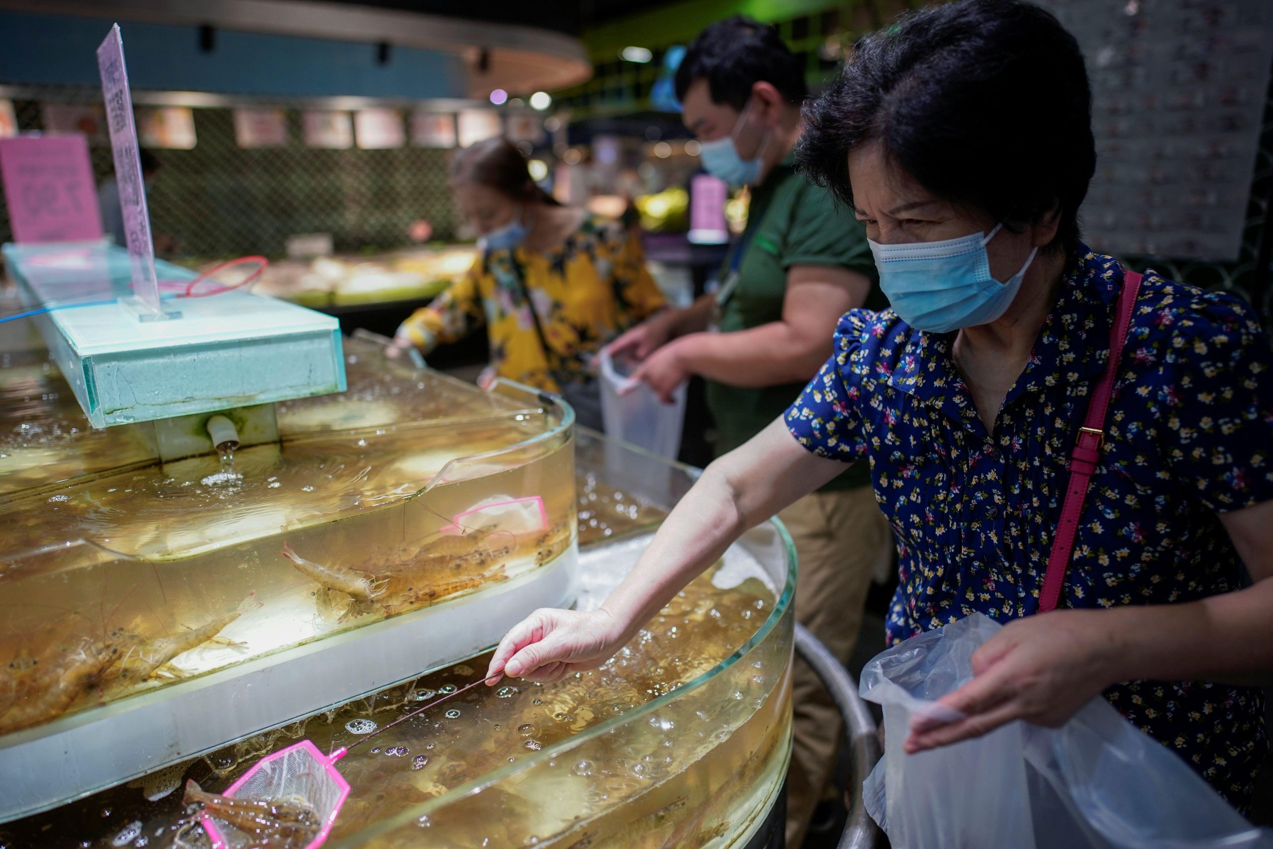 people in a Chinese market buying shrimp