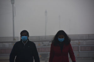 <p>नई दिल्ली में इंडिया गेट के पास नवंबर, 2020 की एक तस्वीर, जिसमें सुबह टहलने आने वाले लोग कोविड-19 से बचाव के लिए मास्क का इस्तेमाल करते दिख रहे हैं और वहां धुंध भी काफी है। [Image: Manish Rajput/SOPA Images via ZUMA Wire/Alamy]</p>