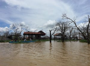 <p>人们划船穿过他们以前居住的克巴罗米村。2017年，柬埔寨北部上丁省湄公河支流桑河上修建了一座大坝，这座村庄被淹没了。图片来源：桑吉查·阿玛查林加姆 / 中外对话</p>