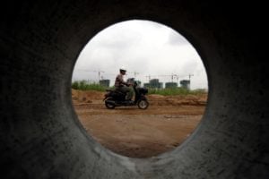 Phnom Penh special economic zone, man rides a motorbike at a construction site