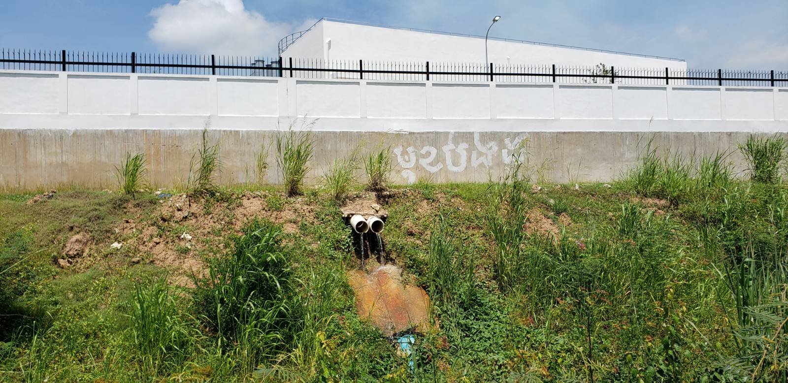 <p>Water drains from pipes outside the Lvea Aem district heavy fuel oil power plant on 20 May 2021. Neighbours claim the effluents have had an impact on papaya and other crops they sell for their livelihoods, in Cambodia’s Kandal province (Image: Danielle Keeton-Olsen / The Third Pole)</p>