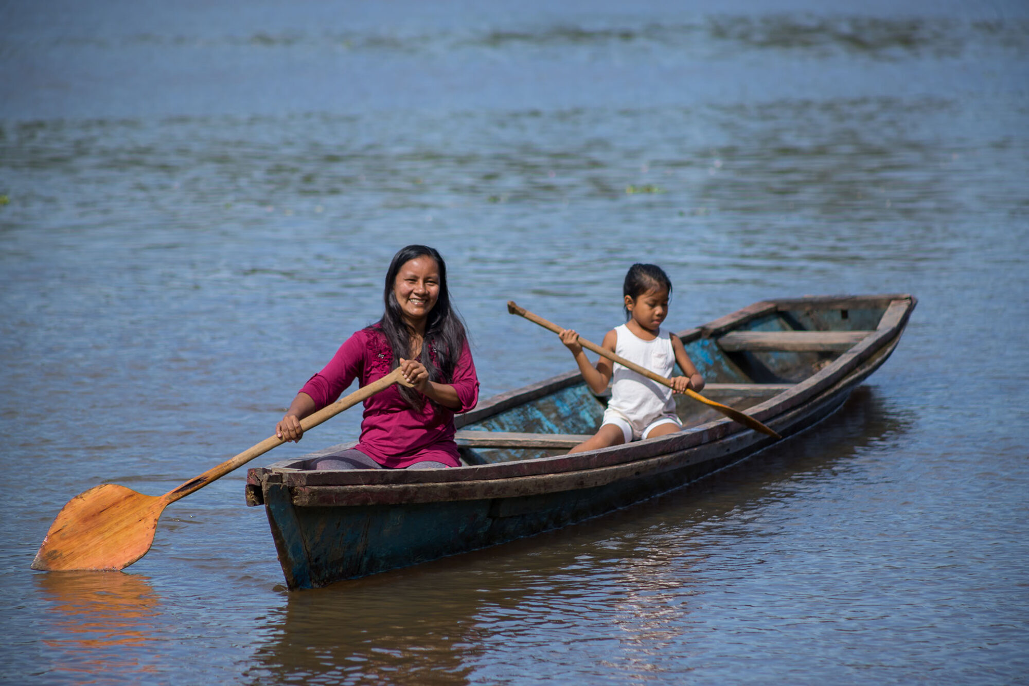 Liz Chicaje Churay é vista em uma canoa remando com sua filha em um rio.
