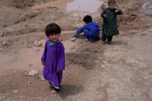 <p>Afghan children play in the mud in an unofficial camp for internally displaced people in Herat, Afghanistan (Image: Charlie Faulkner)</p>