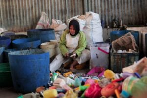A waste collector in Indonesia, sorts through household waste to find recyclable plastics