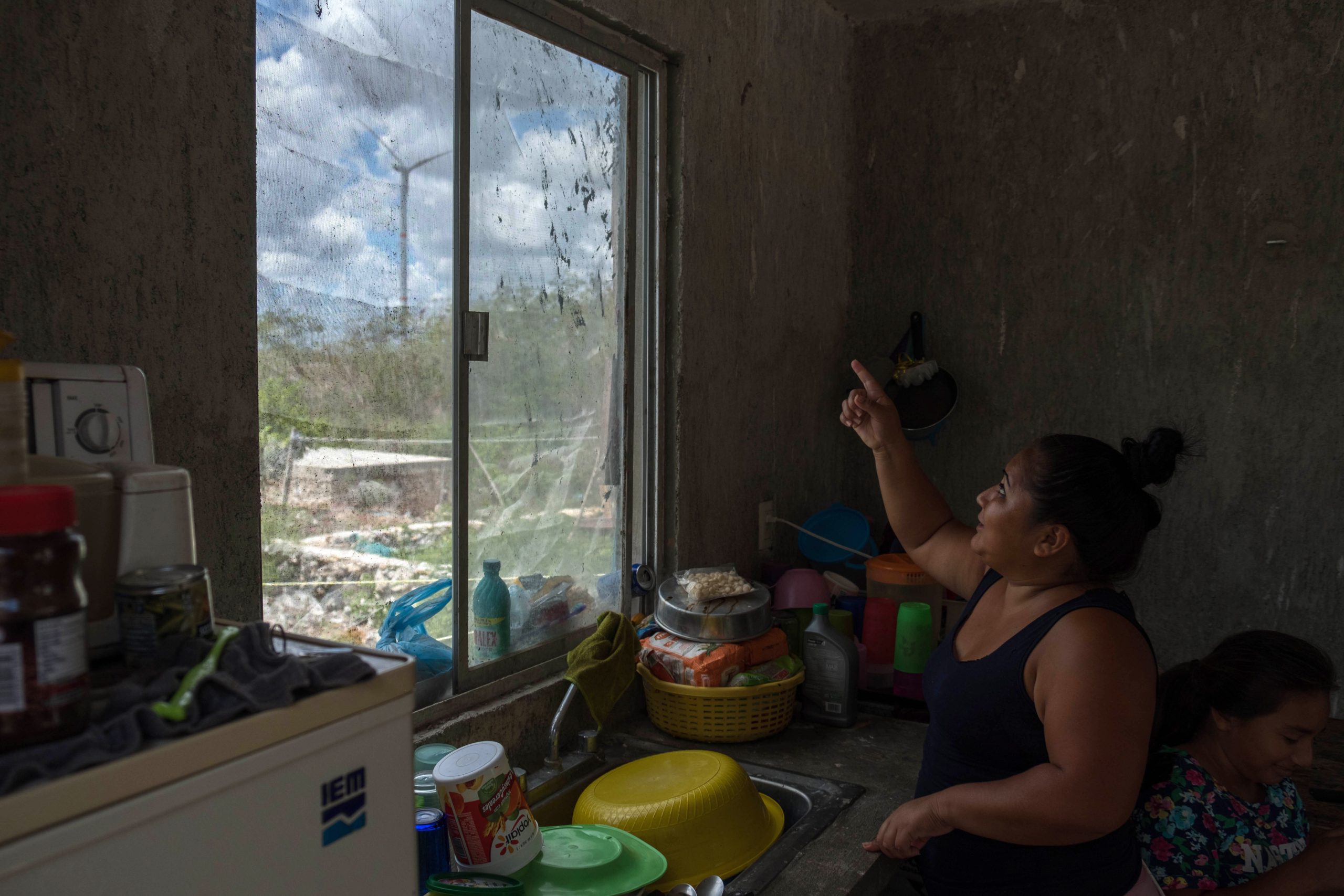 A mulher aponta as turbinas eólicas da janela de sua cozinha