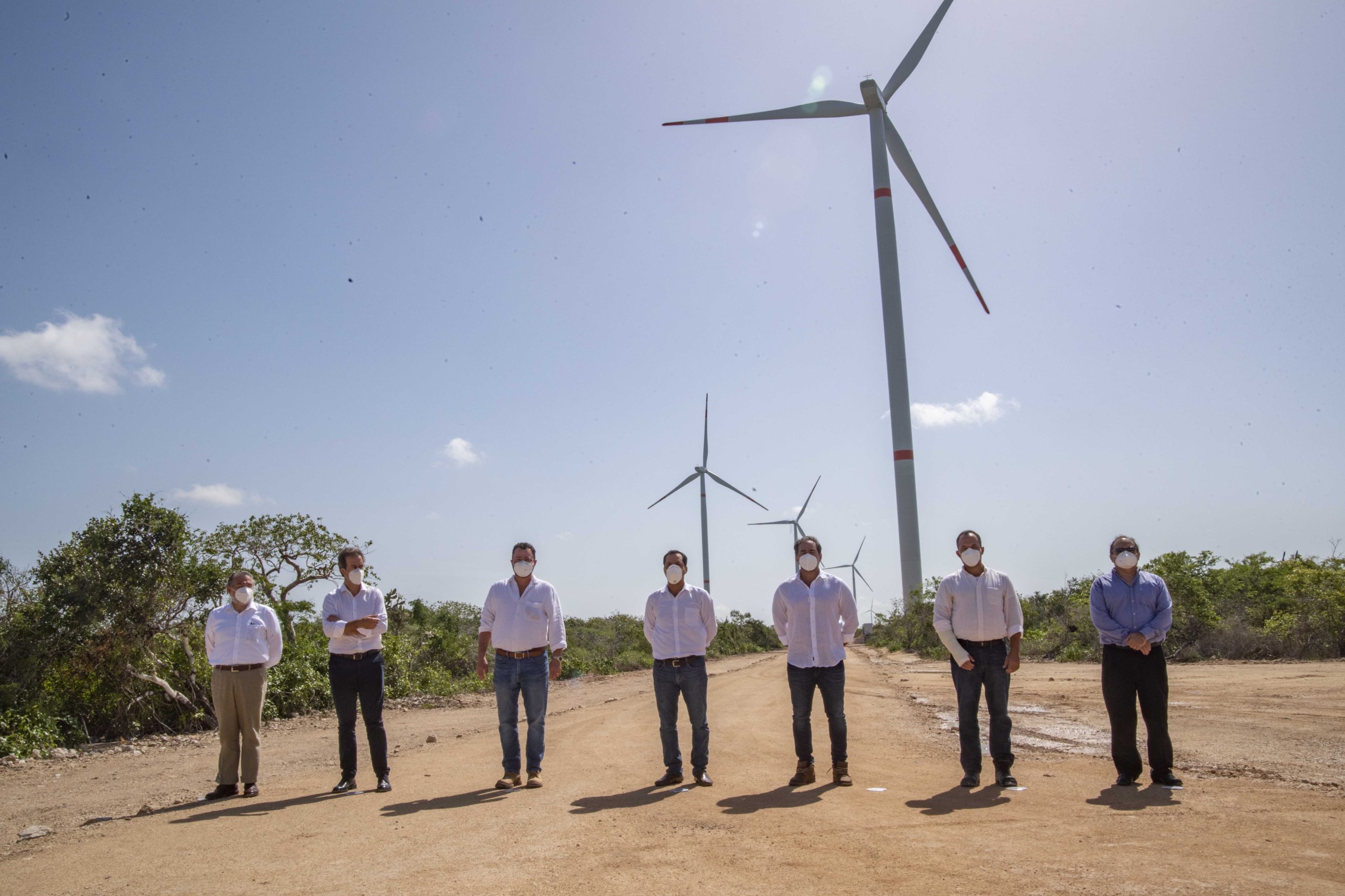 Sete homens em pé diante de moinhos de vento