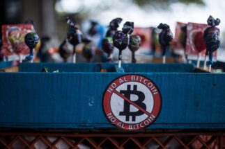 <p>&#8220;Não ao Bitcoin&#8221;, diz um adesivo em uma barraca de rua que vende pirulitos e outros doces. Muitos vendedores ambulantes se opõem à moeda digital. (Víctor Peña / dpa / Alamy Live News)</p>
