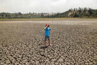 Boy with binoculars on a dry lake in the El Yaki nature reserve, Chile