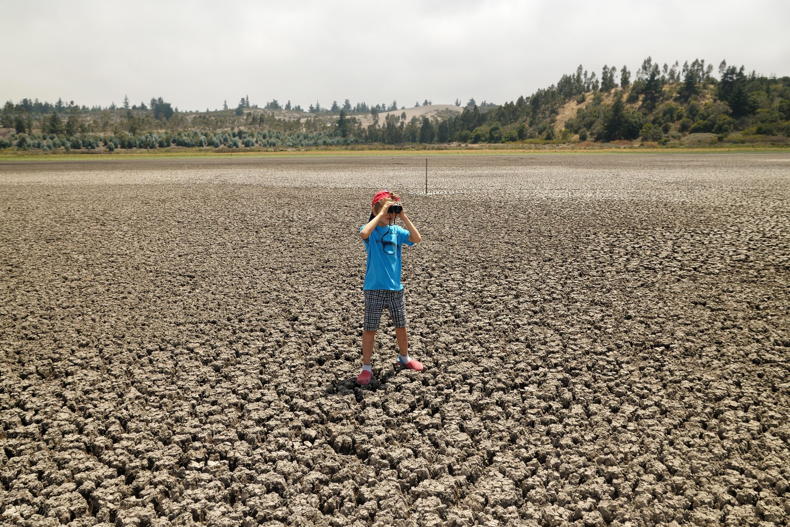 Niño con binoculares en un lago seco 