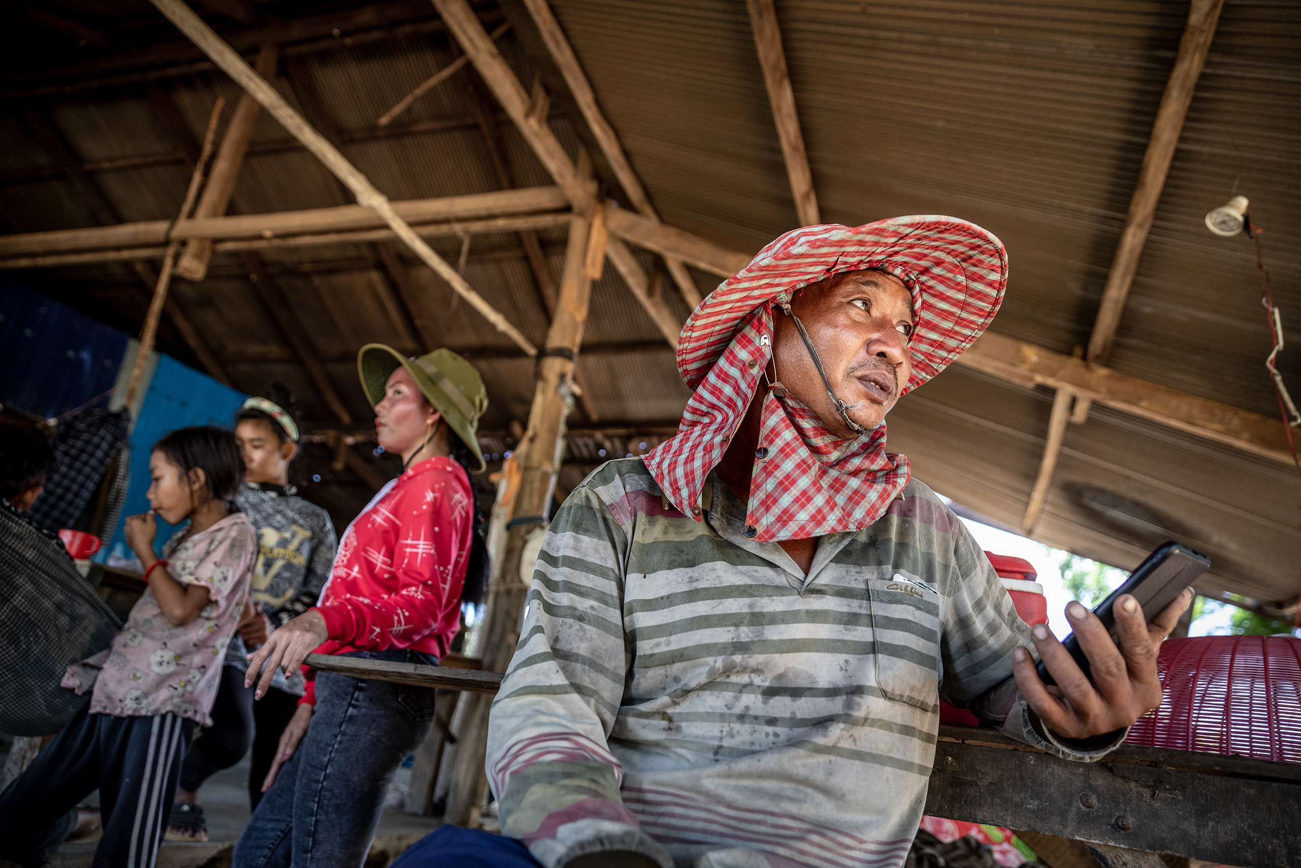 Cambodian mango farmer Cheung Sokha holds his phone with a worried expression on his face